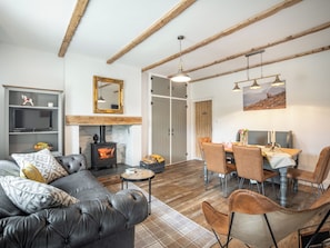 A cozy living room with a fireplace, leather sofa, dining table, and chairs. - The Liddel Haven - UK35337 (Saughtree, near Kielder)