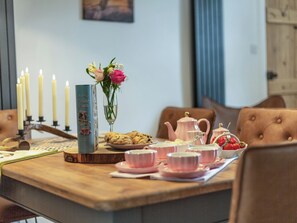 A table set with tea cups, a teapot, cookies, and a candle holder. - The Liddel Haven - UK35337 (Saughtree, near Kielder)