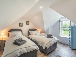 A bedroom with two beds, a window, and a dresser.