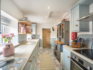 A kitchen with a central island, wooden cabinets, a microwave, a stove, and a small sink.