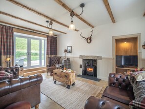 A living room with a fireplace, leather sofas, a wooden coffee table, and a television.