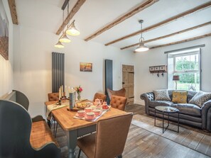 A dining area with a wooden table, chairs, and a window with a view of greenery.