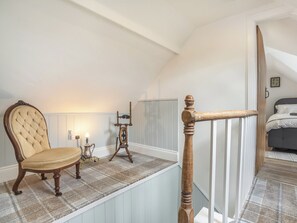 A bedroom with a bed, a nightstand, a lamp, and a chair.