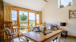 A dining area with a wooden table, chairs, a bottle of wine, and a glass.