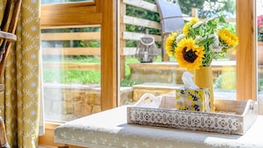 A wooden chair, a table with a decorative tray, and a vase with flowers.