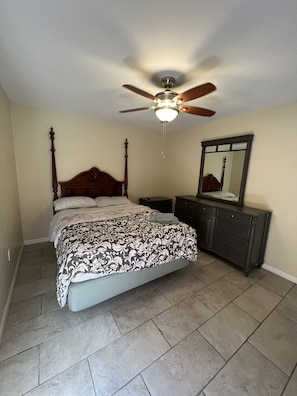 Un dormitorio con cama, cómoda, espejo y ventilador de techo.
