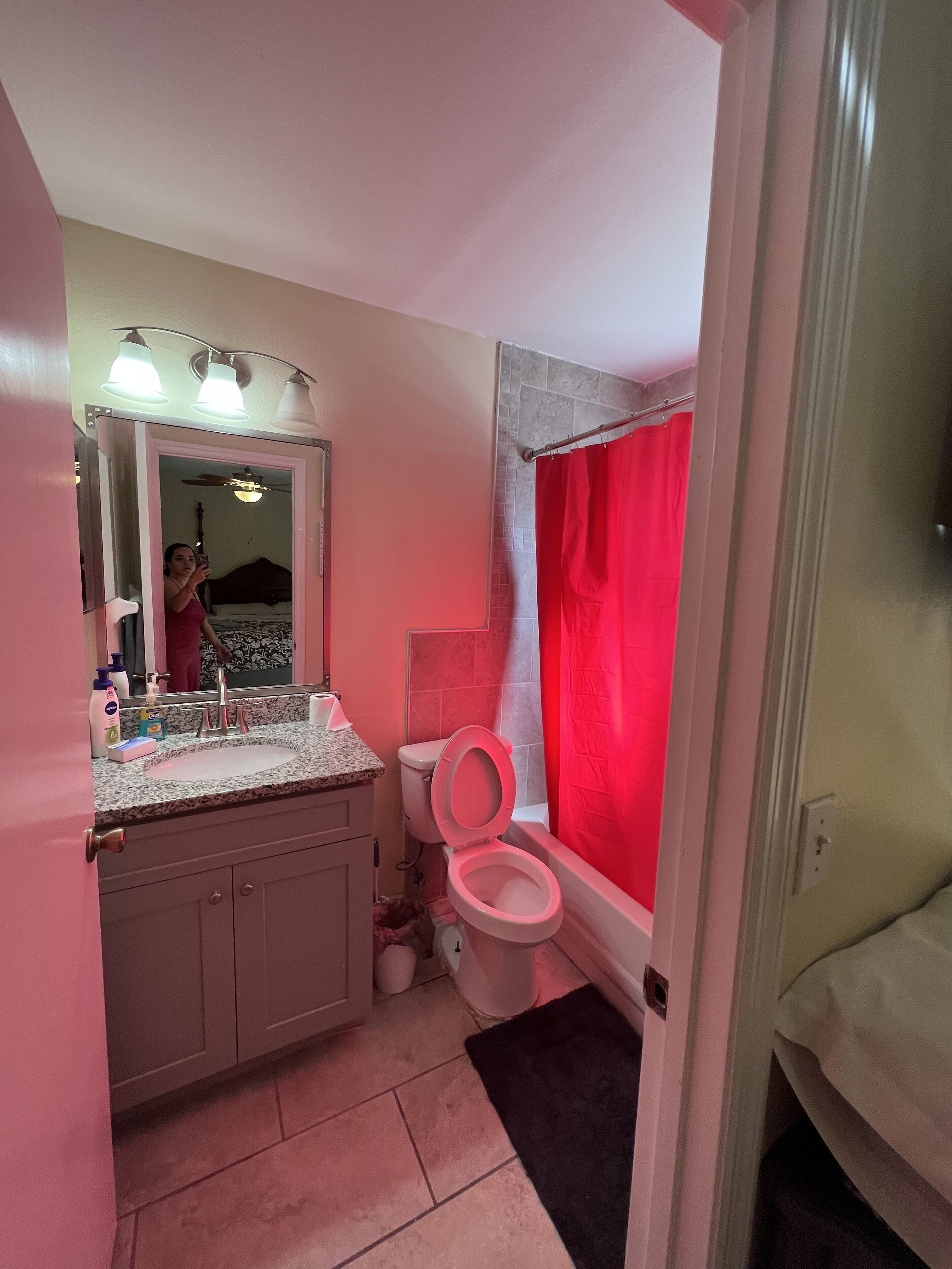 Een badkamer met een roze toilet, een wastafel met een spiegel erboven en een douchegordijn.