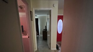 En hall med ett klinkergolv, en dörr med ett runt fönster och en svart korg.