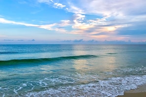 Enjoy a serene beach experience with gentle waves lapping onto the shore.
