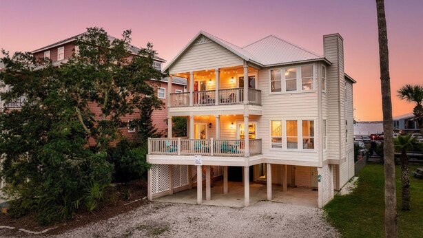 Ein zweistöckiges Haus mit Balkon, überdachter Veranda und Garage.