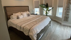 Un dormitorio con una cama grande, un lámpara en el techo y una ventana con persianas.