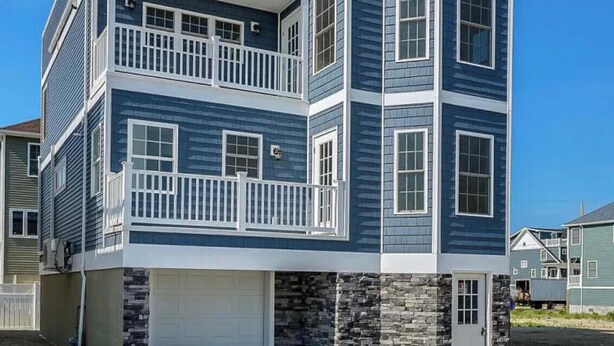 Un edificio residencial de varios pisos con garaje, balcones y cimientos de piedra.