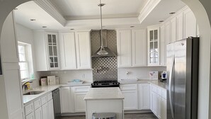 Una cocina moderna con armarios blancos, un refrigerador de acero inoxidable y una isla central.
