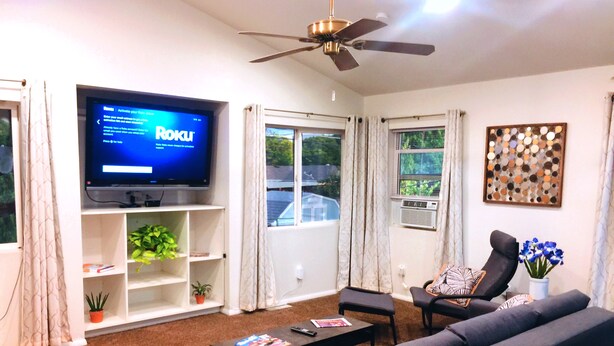 A living room with a flat-screen TV, a ceiling fan, a sofa, a coffee table, and a potted plant. - 1,200 SqFt Comfy Home, 15 min to Boulder (Broomfield)