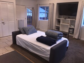 Ein Schlafzimmer mit einem Bett, einem Fernseher und einem Fenster.