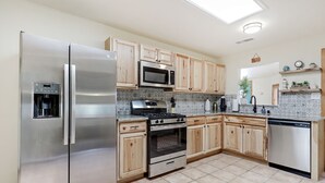A modern kitchen with stainless steel appliances, wooden cabinets, and a tiled backsplash. - 5 min  to Old Town - Prime location - Game Room - gated parking  (Albuquerque)