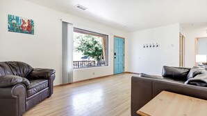 A spacious living room with a large window, a blue door, and two sofas. - 5 min  to Old Town - Prime location - Game Room - gated parking  (Albuquerque)