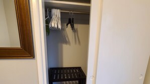 Vasemmalla puolella on vaatehuone, jossa on puinen penkki, henkariteline ja peili.