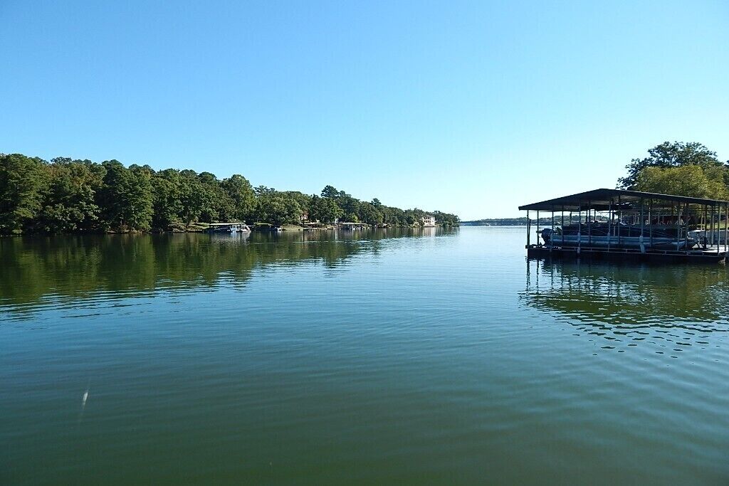 Un lago tranquilo con un muelle y una estructura cubierta.
