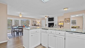 Una cocina moderna con armarios blancos, encimeras de granito y un comedor con mesa y sillas.