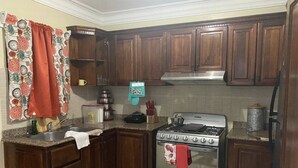 Une cuisine avec des meubles de rangement en bois, une cuisinière et un évier.