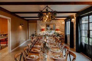 A dining area with a long table set for a meal, surrounded by chairs. - The Farmstead - Family Accommodation (Dixons Creek)