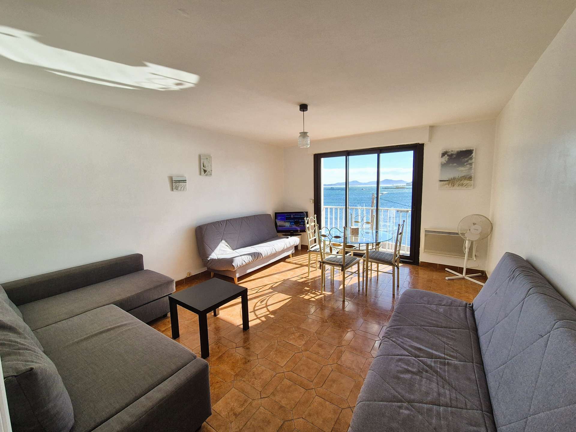 Ein Wohnzimmer mit einer Couch, einem Couchtisch, einem Fernseher und einem Balkon mit Blick.