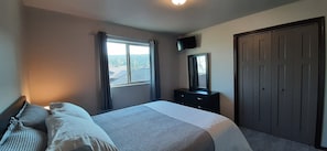 A bedroom with a bed, a dresser, a TV, and a wardrobe.
