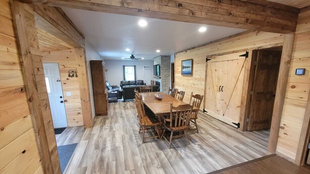 Un intérieur en bois avec une table à manger, des chaises et un canapé à l’arrière-plan.