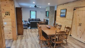 L’intérieur d’un chalet en bois comprend une table à manger, des chaises, un canapé et une cheminée.