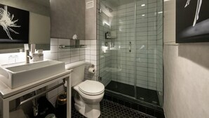 A modern bathroom with a glass-enclosed shower, a white sink, and a toilet.
