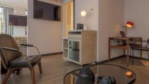 A modern room with a flat-screen TV, a glass coffee table, a laptop, and a chair.