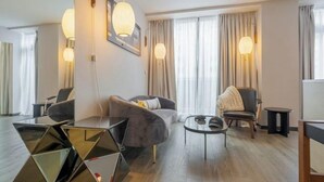 A modern hotel room with a sofa, armchairs, a coffee table, and decorative lighting. - Pestana CR7 Times Square (New York)