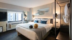 A modern hotel room with a large bed, a TV, a window, and a bathroom with a towel rack.