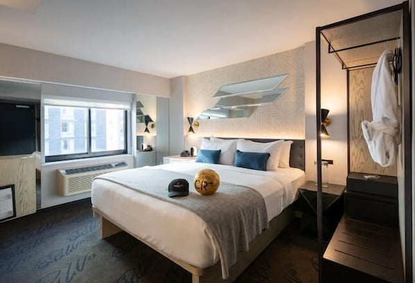 A modern hotel room with a large bed, a TV, a window, and a bathroom with a towel rack. - Pestana CR7 Times Square (New York)