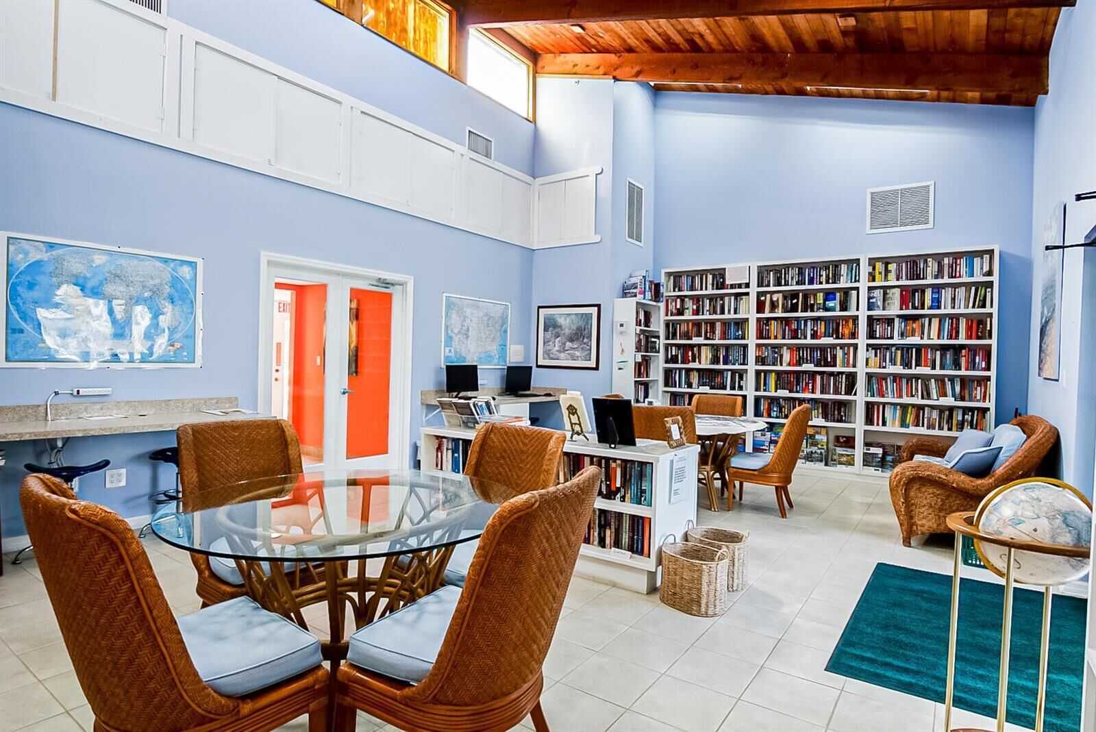 A spacious living room with a large bookshelf, comfortable seating, and a dining area.