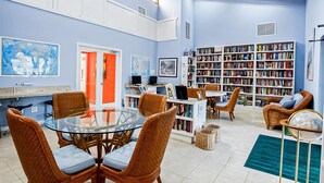 A spacious living room with a large bookshelf, comfortable seating, and a dining area. - 🏖️Just Remodeled! The Ocean Cottage at Ocean Village Beach Condo (Fort Pierce)