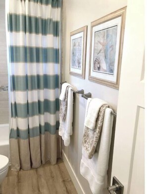 Een bad/douchecombinatie, een haardroger, handdoeken, toiletpapier