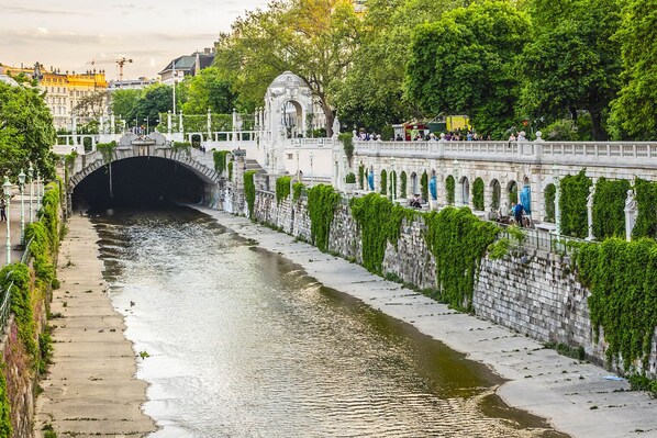 A stone bridge with a tunnel, surrounded by greenery and a river.