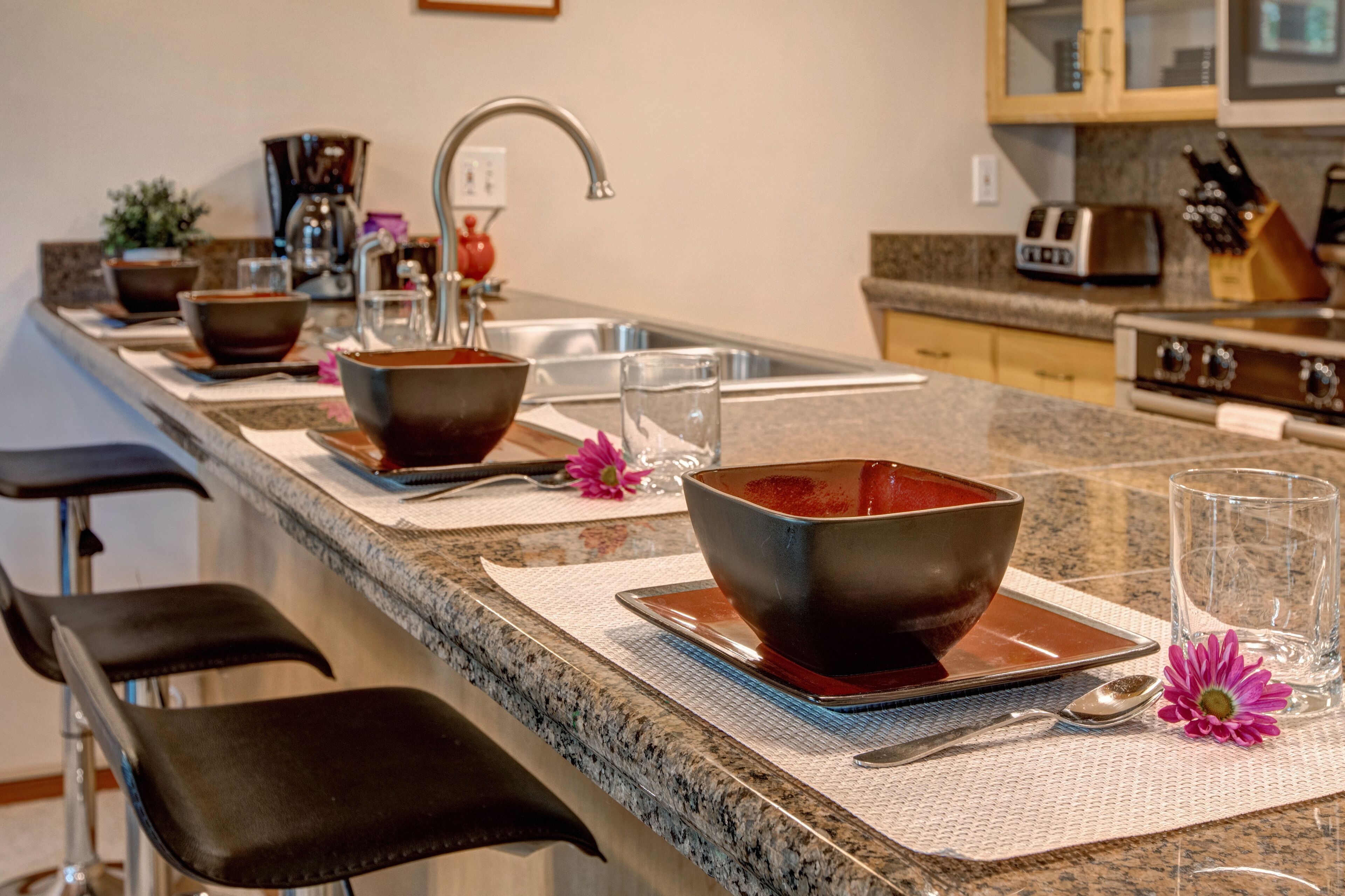 Fully Equipped Kitchen with stone countertops, stainless steel appliances, and bar seating for four