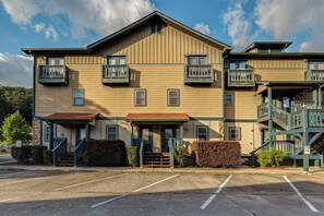 A two-story building with a central entrance, a staircase on the right, and a parking lot in front.