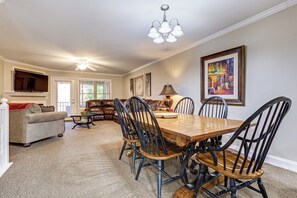 A dining area with a wooden table and chairs, a sofa, a fireplace, and a ceiling fan.