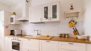 A modern kitchen with white cabinets, a microwave, an oven, a sink, and a wooden countertop. - Casa di Nonno by Interhome (Cividale)