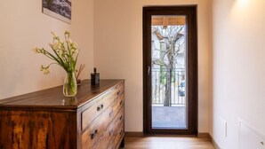 A hallway with a wooden dresser, a vase with flowers, a framed picture on the wall, and a door leading to an outdoor area. - Casa di Nonno by Interhome (Cividale)