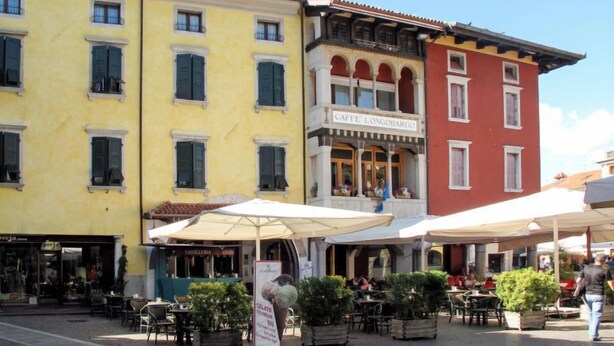 A street with outdoor seating at a cafe, a building with a sign reading "CAFFÈ LONGOBARDO", and another building with a shop. - Casa di Nonno by Interhome (Cividale)