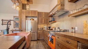 Una cocina moderna con armarios de madera, electrodomésticos de acero inoxidable e iluminación colgante.