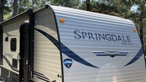 A white RV with 'SPRINGDALE' branding, a 3-year warranty badge, and a propane tank. - Gennesis RV is located in Lost Pines Near Bastrop Lake (Bastrop)