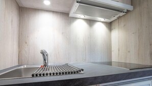 Eine moderne Küche mit Spüle aus Edelstahl, einer schwarzen Arbeitsplatte und Holzvertäfelung.