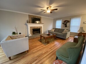Ein Wohnzimmer mit Kamin, einer Couch, einem Sessel und einem Couchtisch.