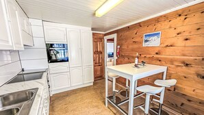Una cocina compacta con armarios blancos, una encimera de mármol y una pared de madera.